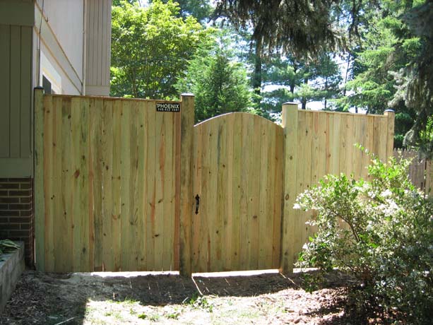 Flat board fence made of pressure treated (PT) pine with 6 inch dip, with a cedar gate